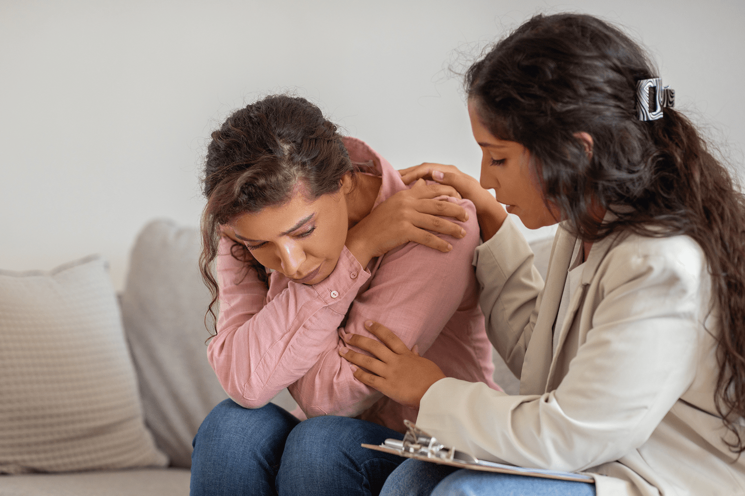 Counselor comforting distressed woman on couch