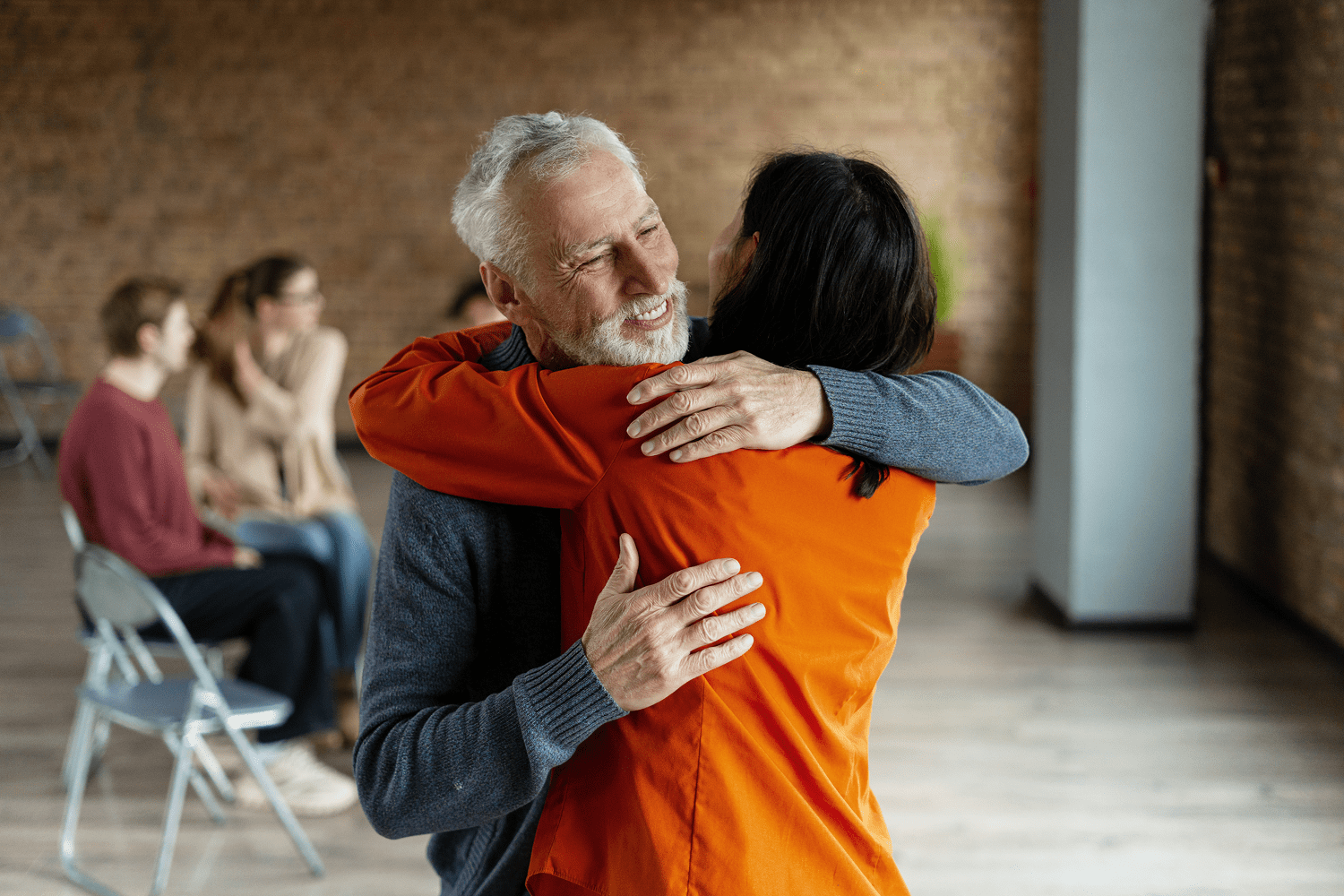 Older man hugging woman in support group