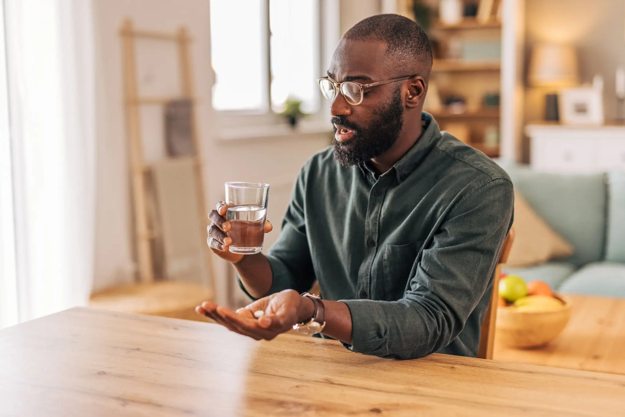 Man holding pill and glass of water