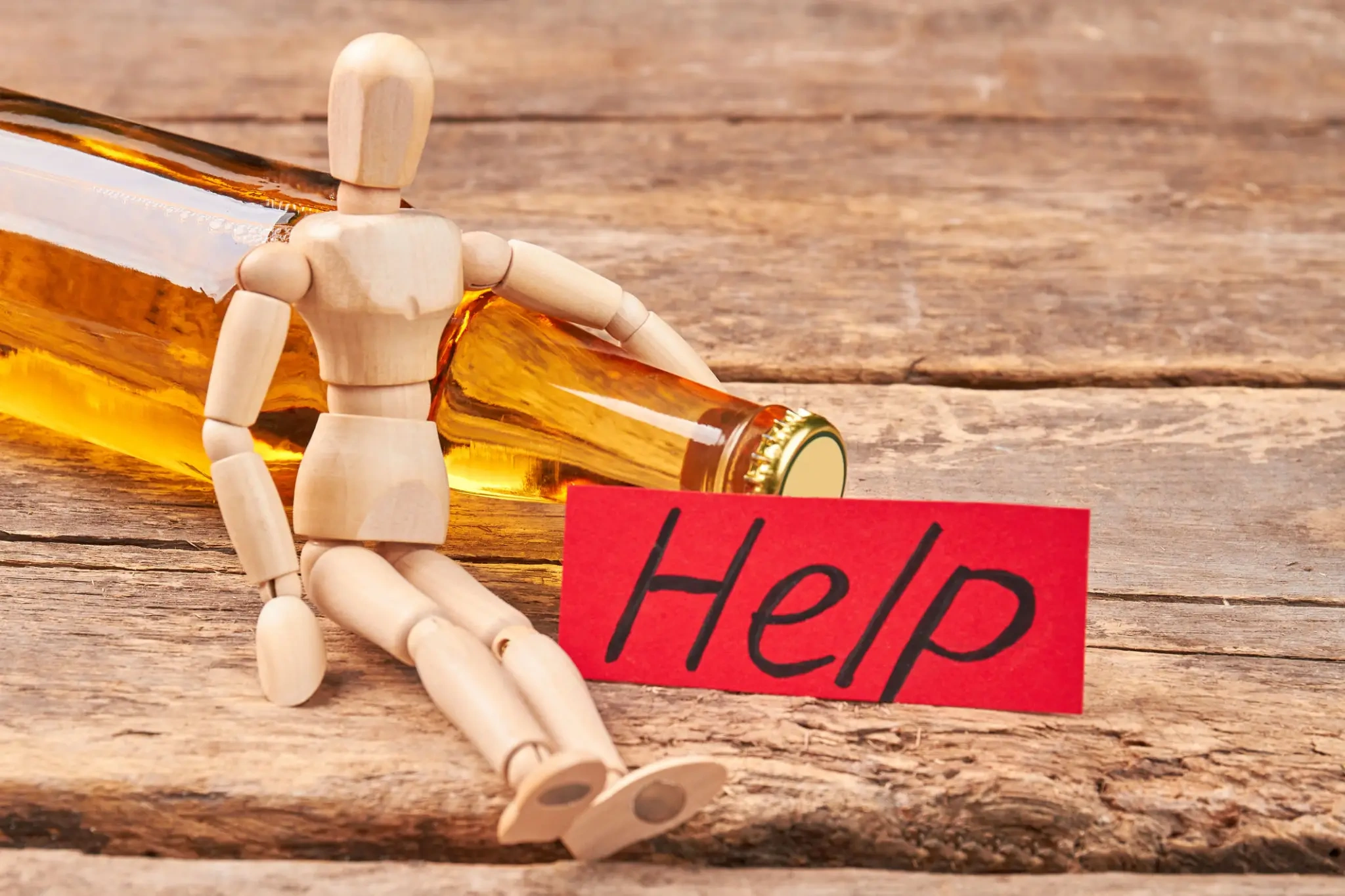 Mannequin leaning against alcohol bottle with "Help