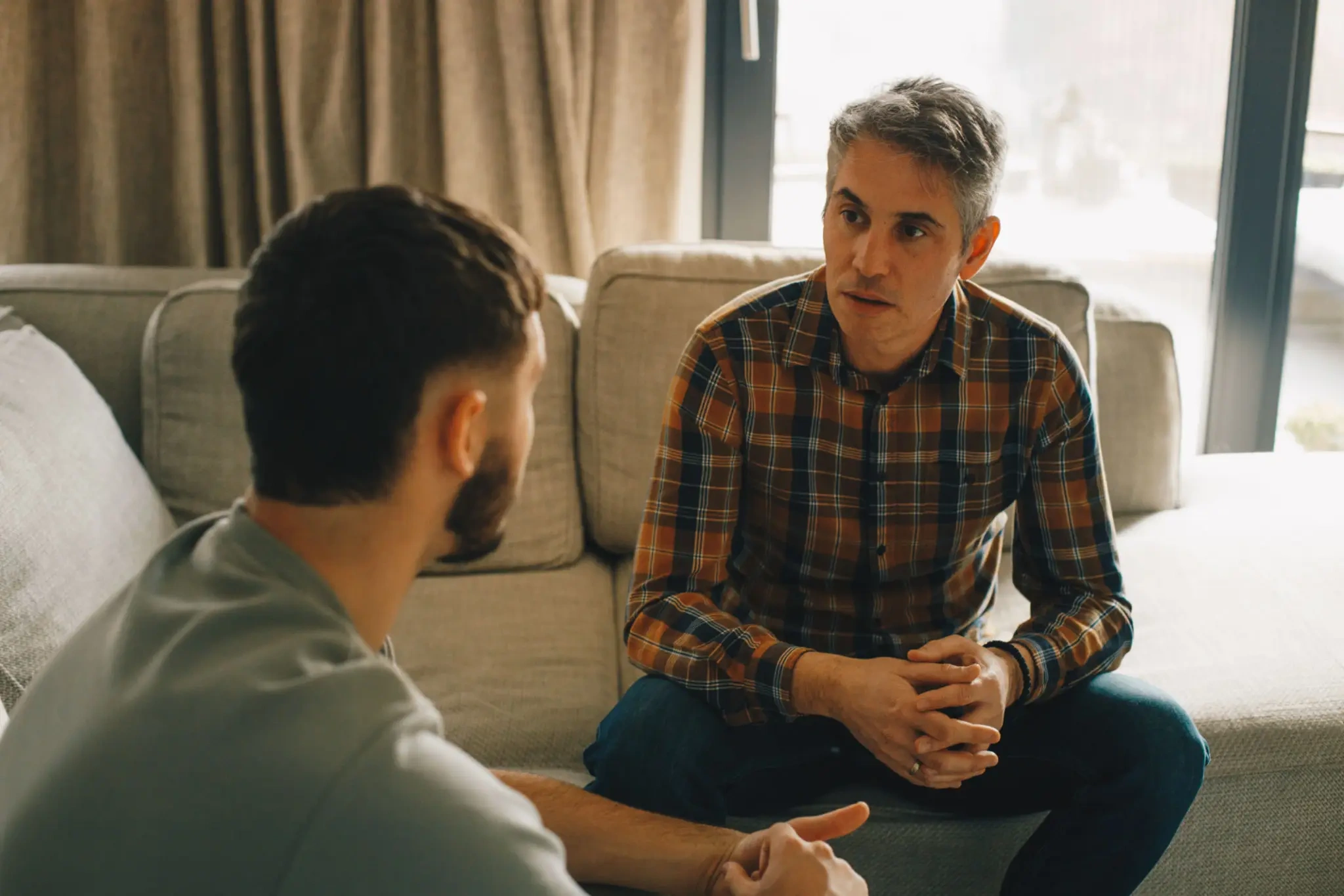 Two men having serious conversation on couch