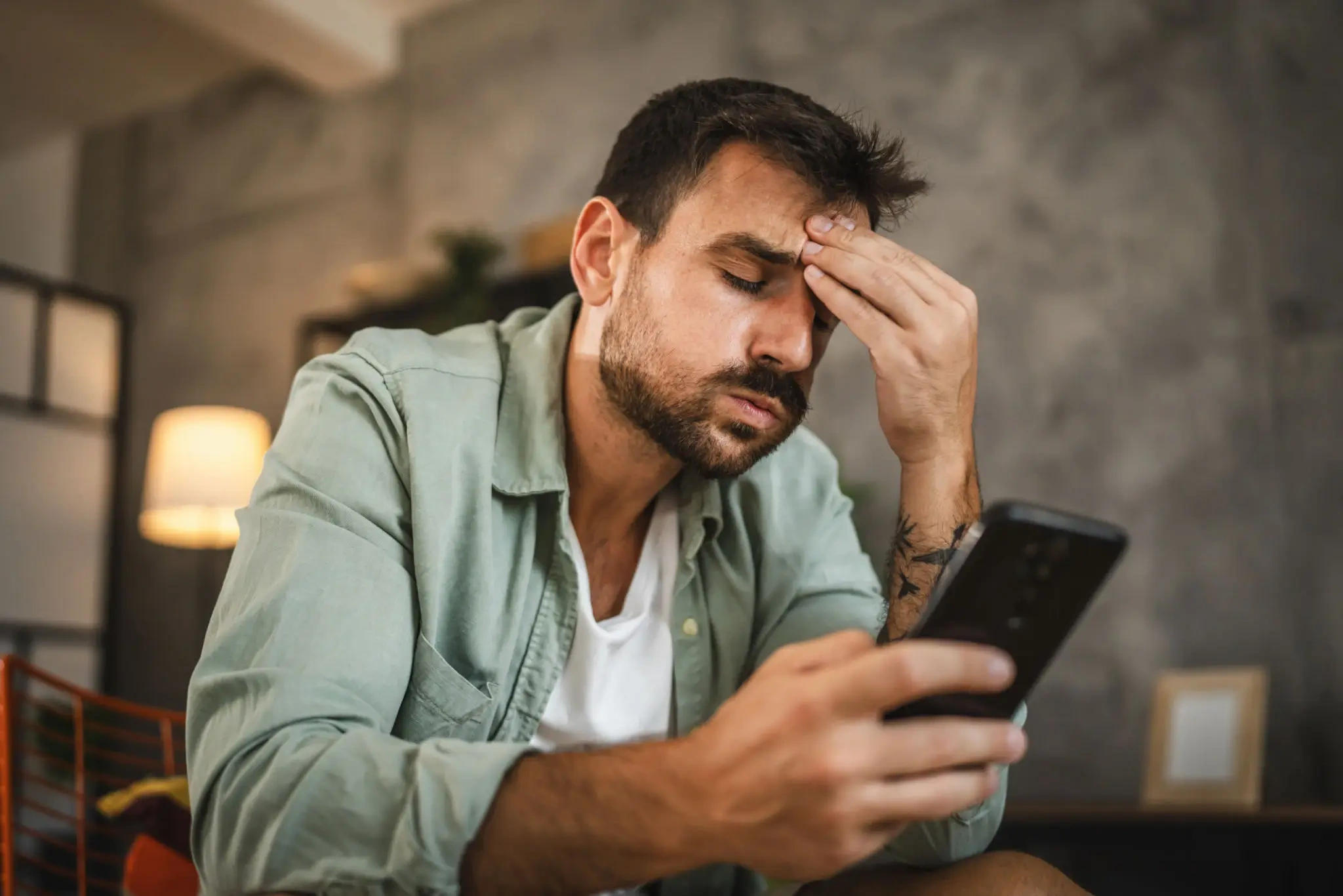 Stressed man checking smartphone in living room
