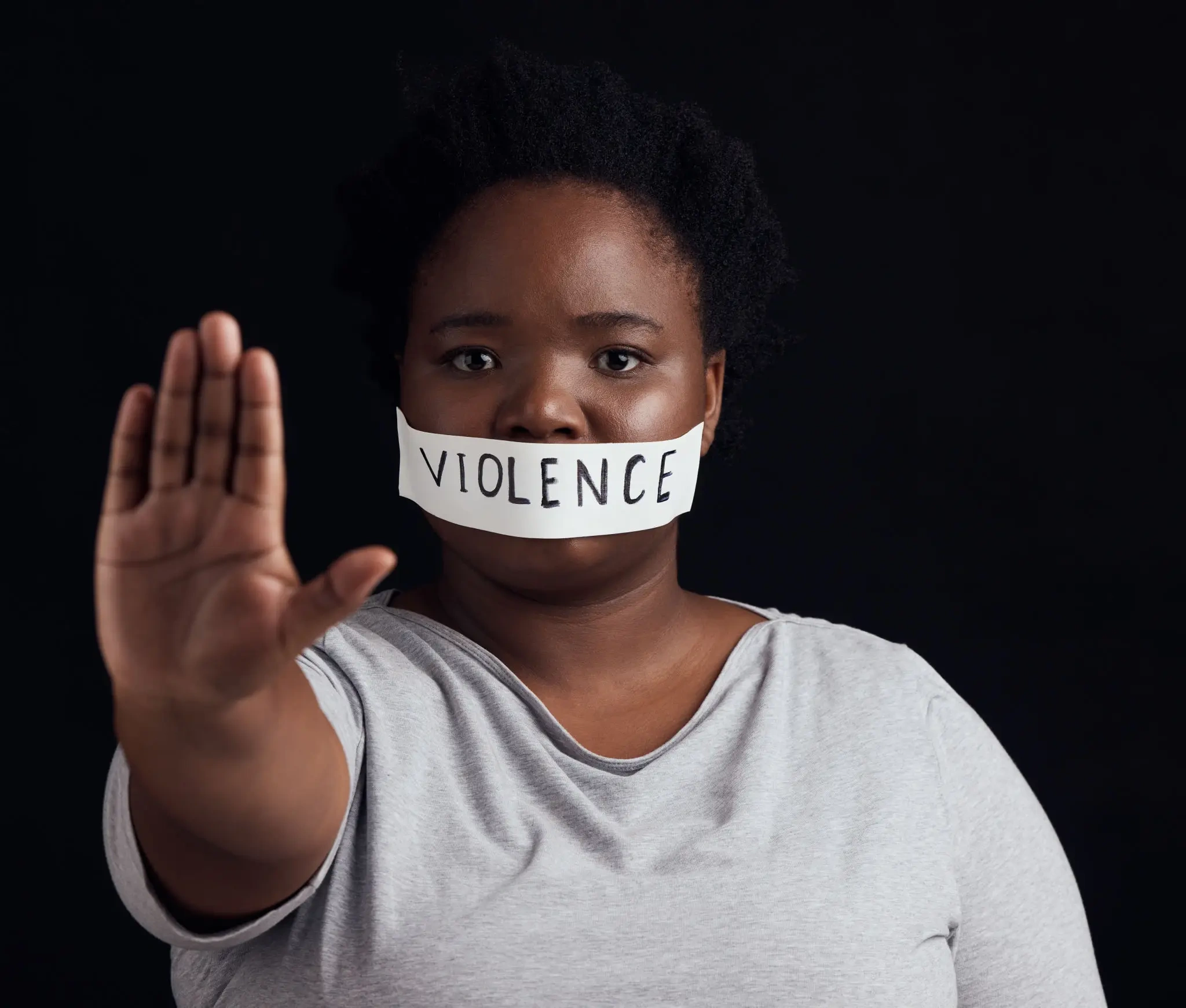 Person with "VIOLENCE" tape, hand raised to stop