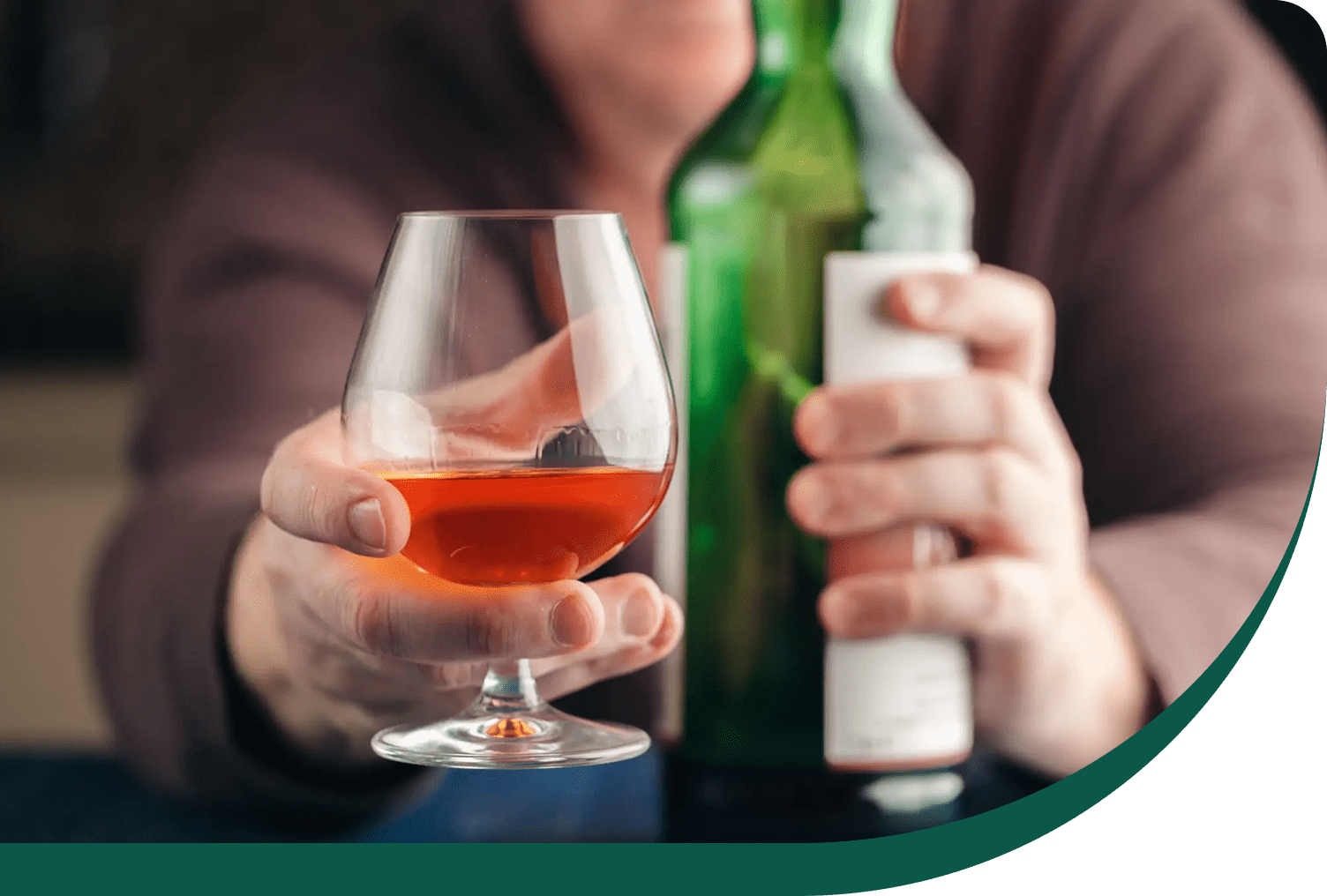 Hand holding snifter glass with amber liquor
