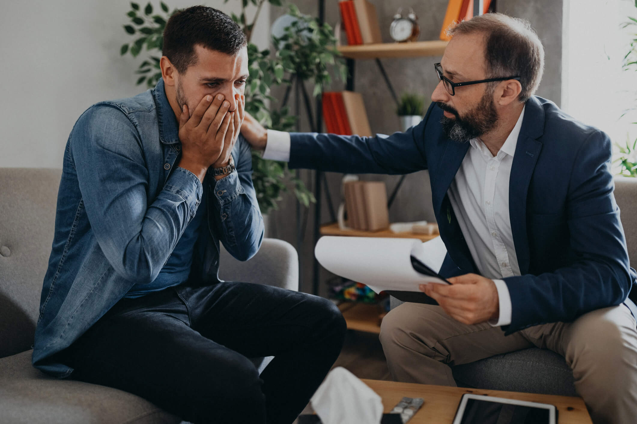 Therapist comforting distressed man during counseling session