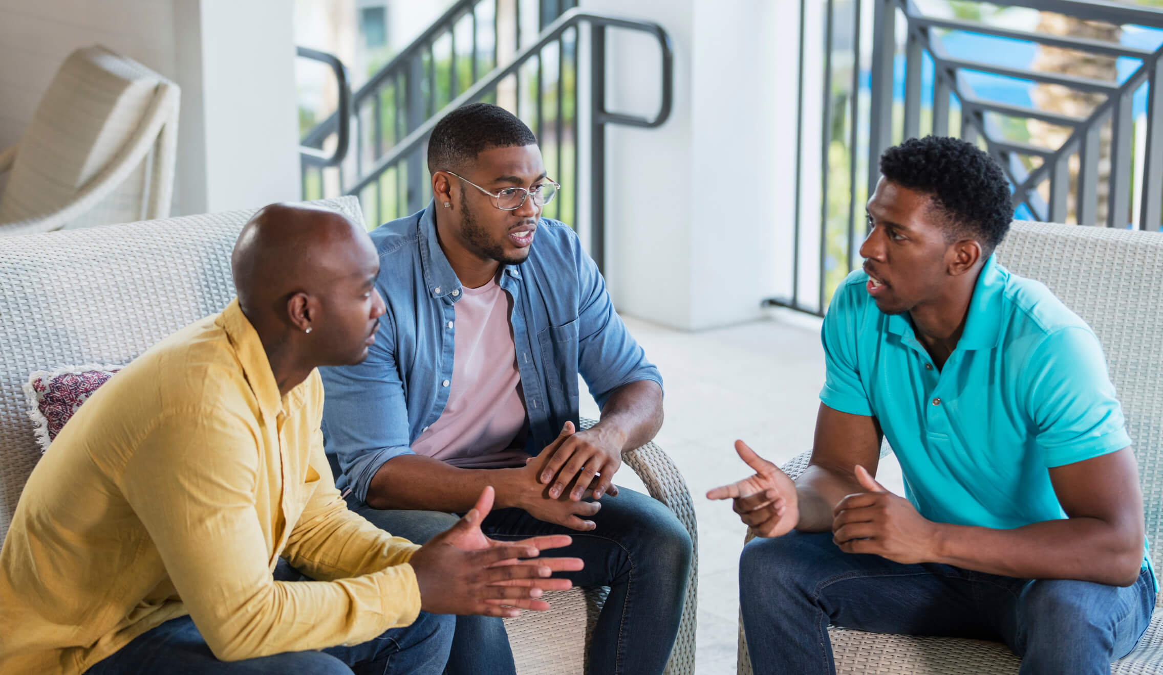 Three men engaged in serious conversation on sofa