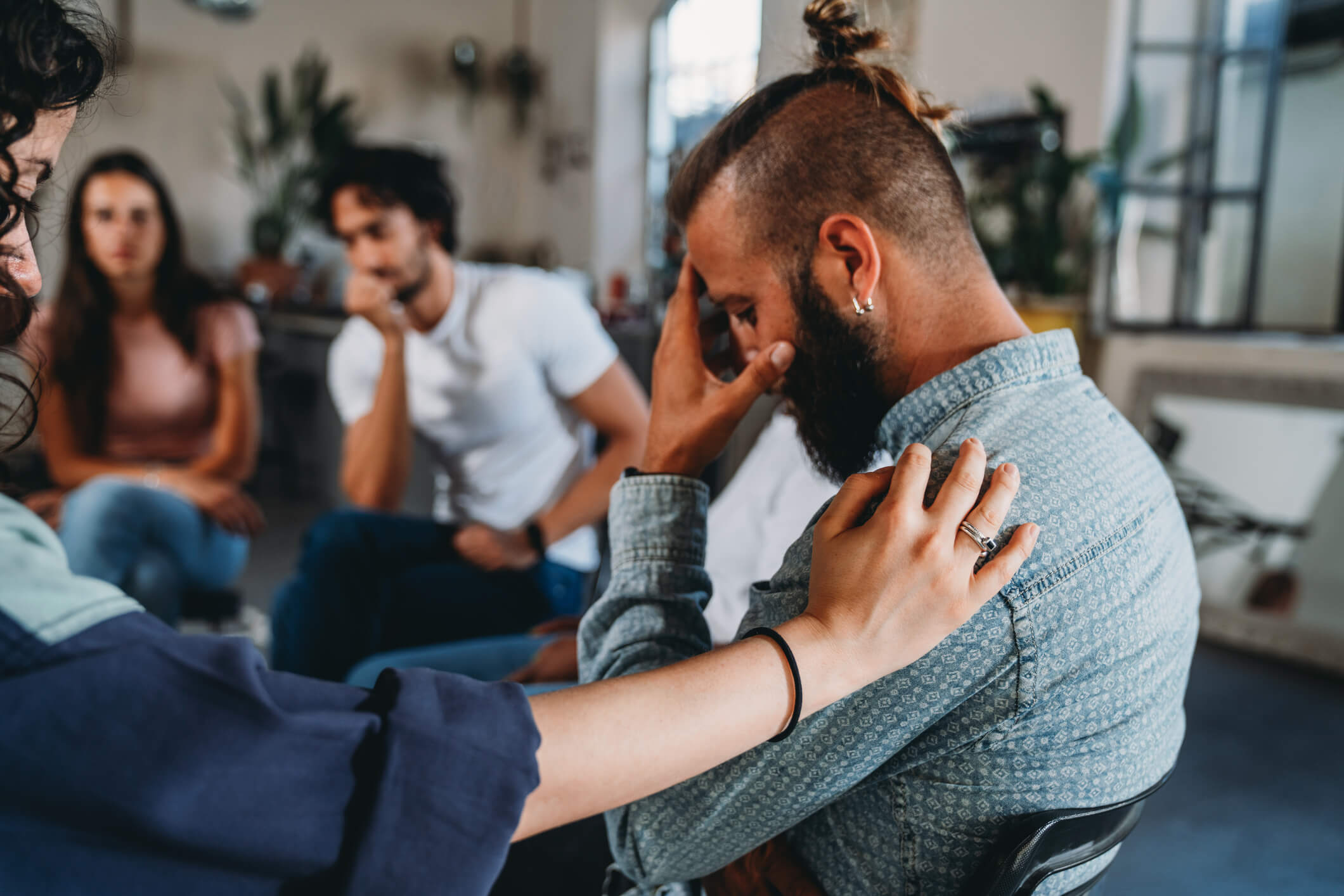 Person distressed in group therapy, peer offers comfort