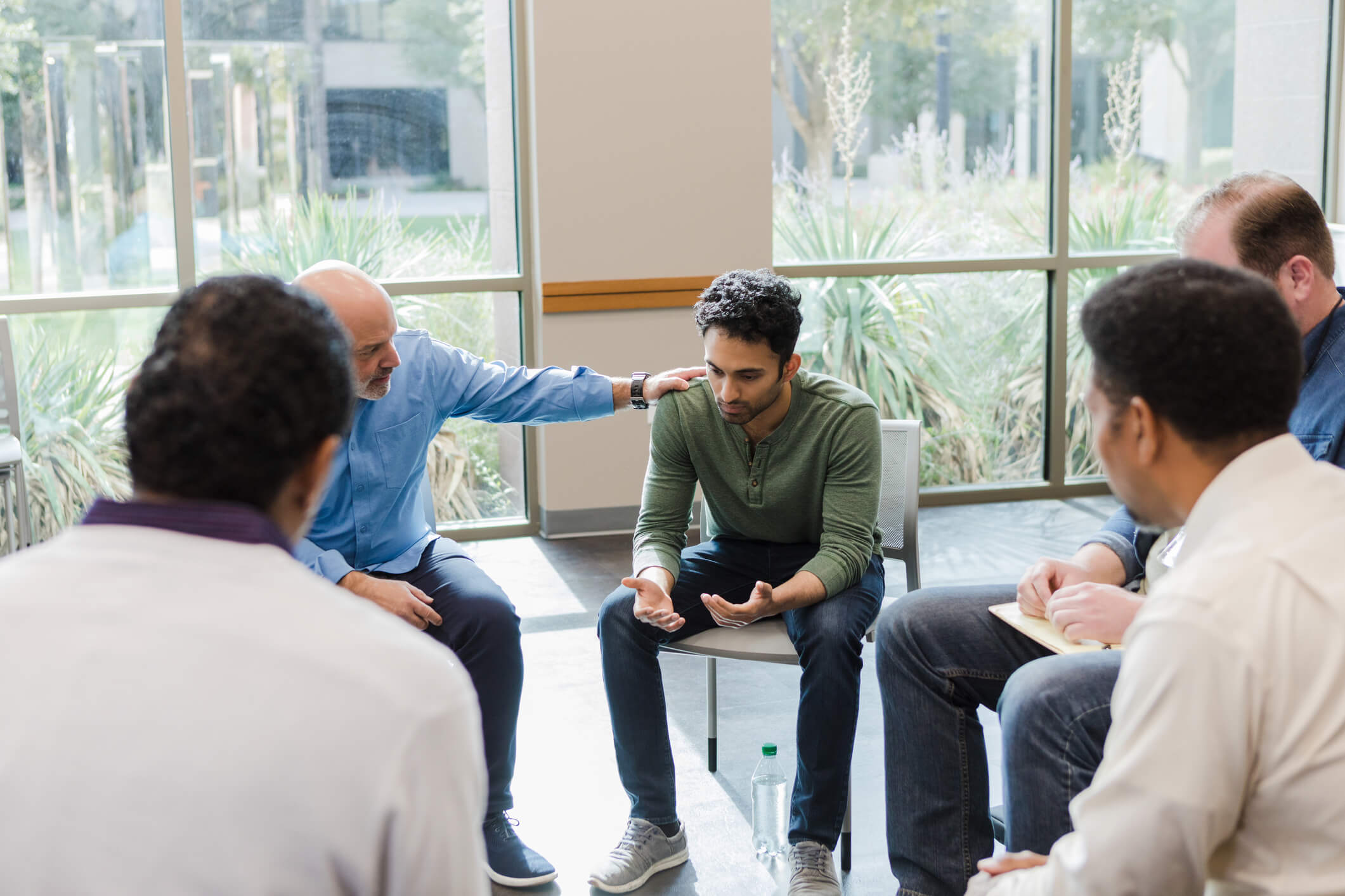 Group therapy session comforting distressed man