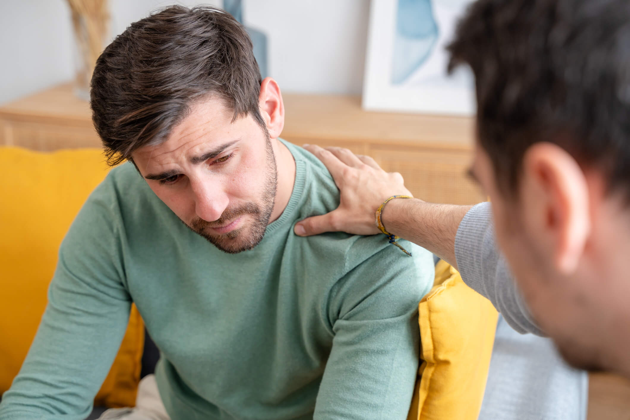 Man comforting distressed friend on couch