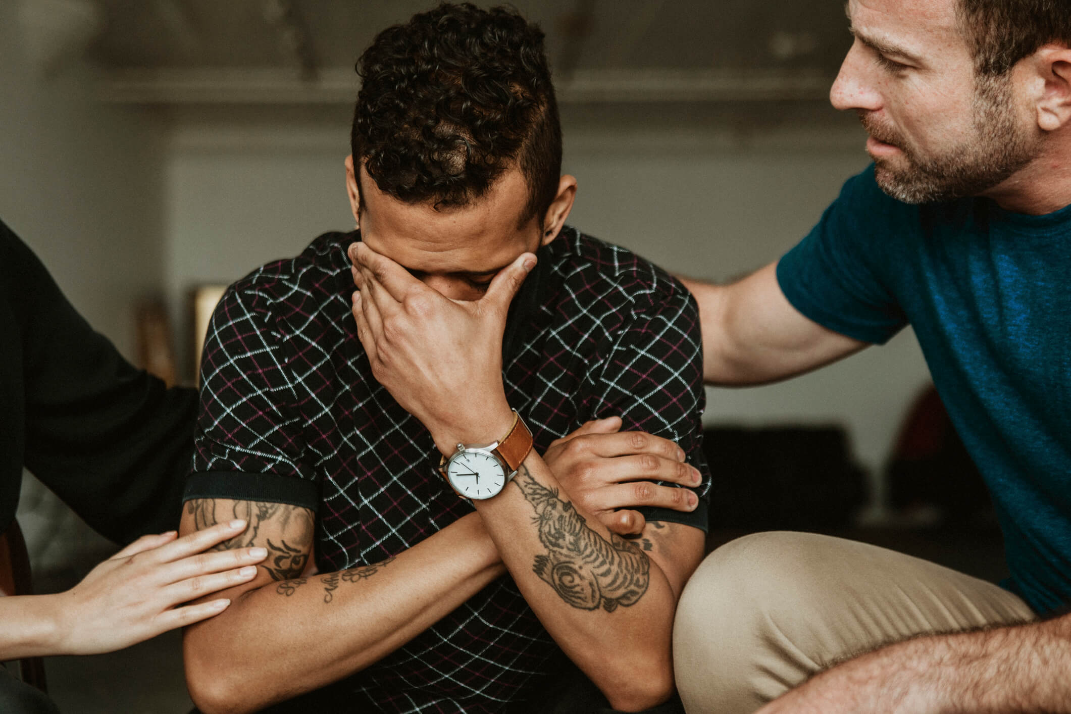 Distressed man comforted by two people