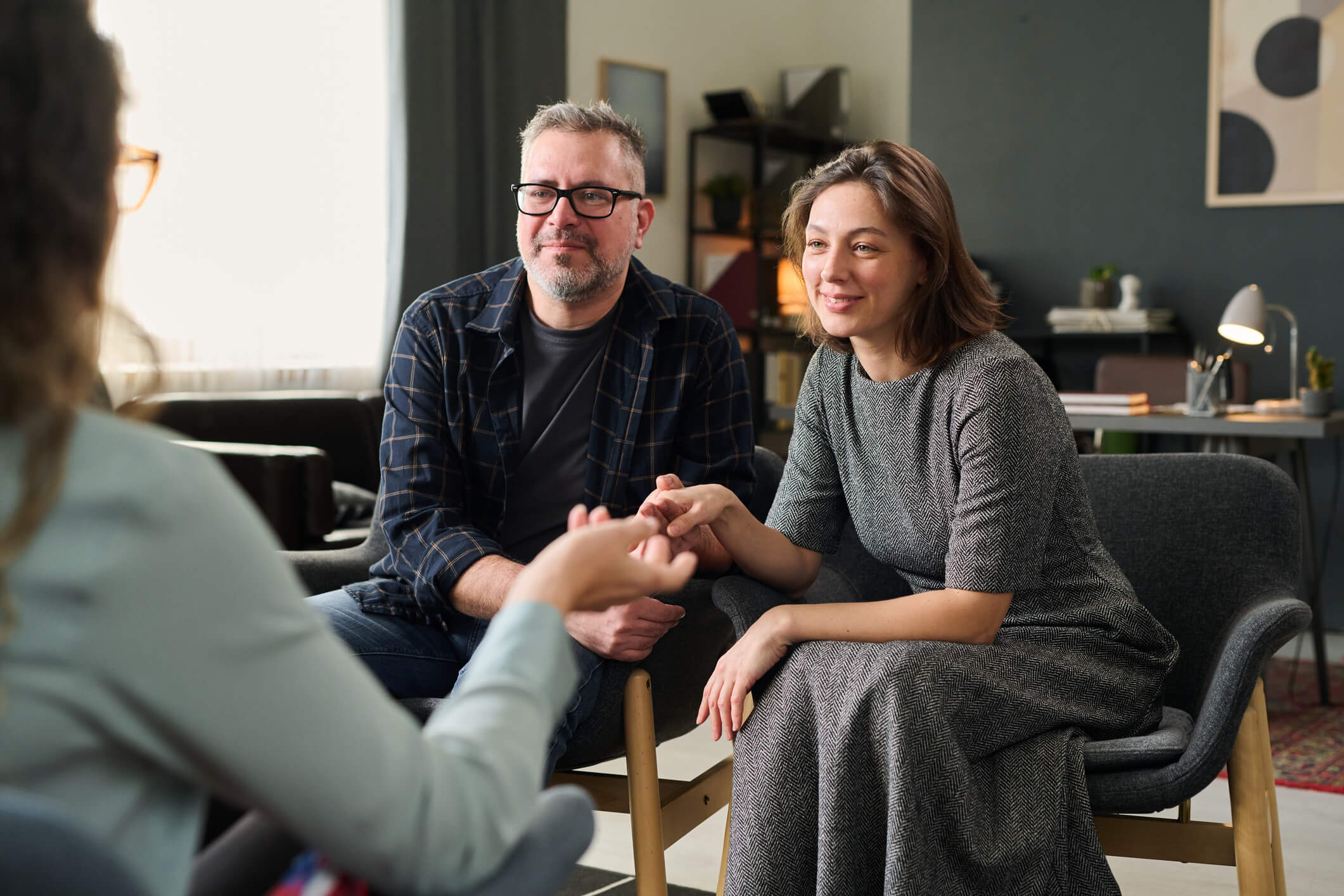 Smiling couple holding hands during counseling session