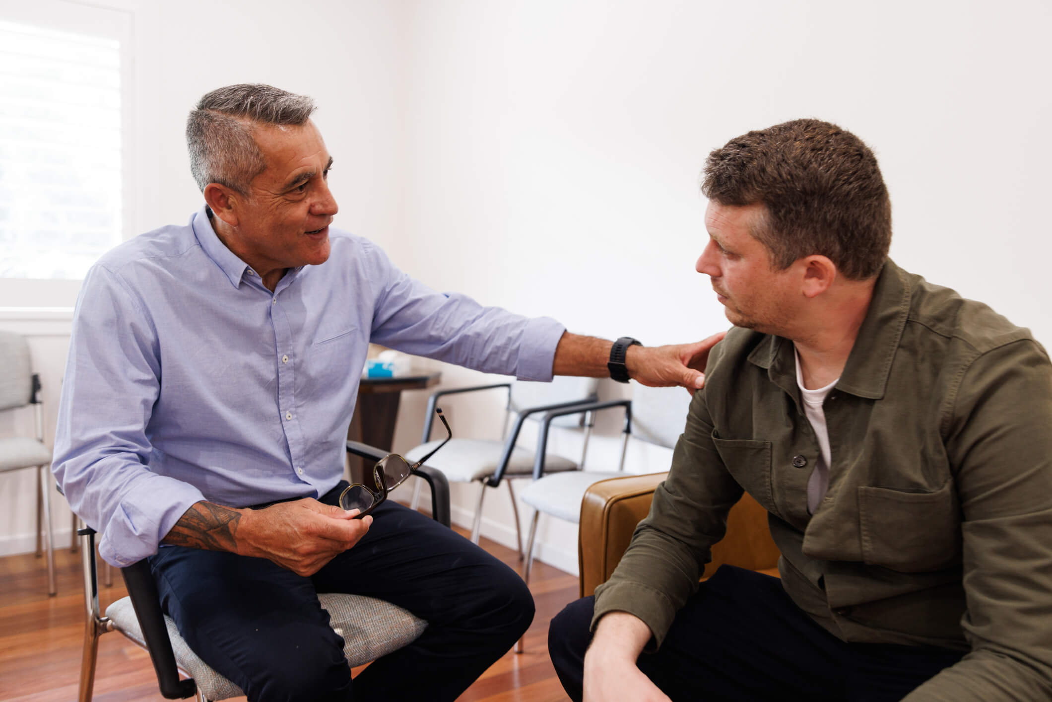 Man comforting another man during counseling session