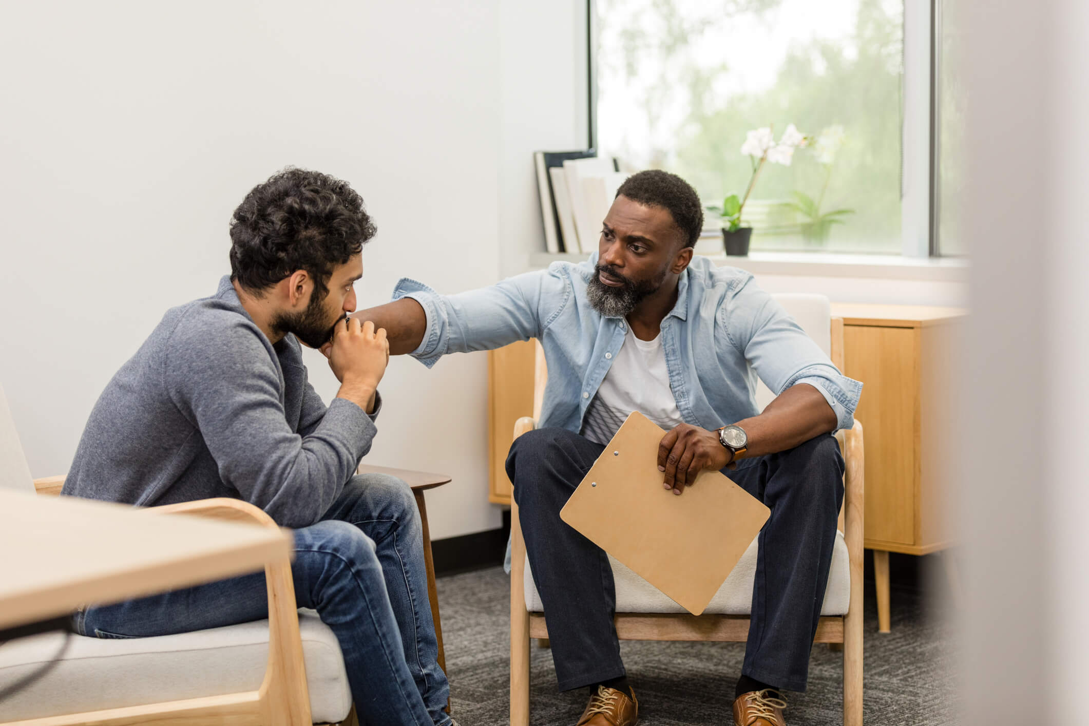 Therapist gently comforting young man in counseling